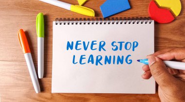 Elyazısı asla renkli kalemler ve ahşap bir masa üzerindeki geometrik şekiller eğitimi ve büyümeyi sembolize eden bir defterde öğrenmeyi bırakmaz..