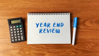 Yıl Sonu Değerlendirmesi, bir deftere hesap makinesi ve tahta bir masa üzerinde iş finansmanı ve değerlendirmesi için yazıldı..