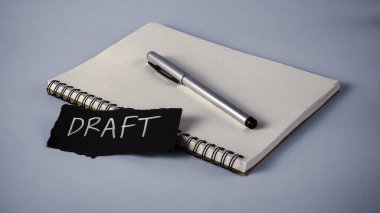 Bir Belge Hazırlama Konsepti: Not Defteri, Gümüş Kalem ve Beyaz Taslak Metni ile Siyah Kağıt