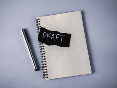 Bir Belge Hazırlama Konsepti: Not Defteri, Gümüş Kalem ve Beyaz Taslak Metni ile Siyah Kağıt