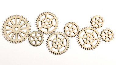 Flat lay of various sizes laser cut wooden gear wheels connected in mechanism on white background