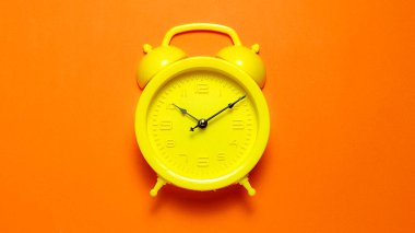 Yüksek karşıtlık kavramları için parlak turuncu arkaplan merkezli canlı sarı alarm saati