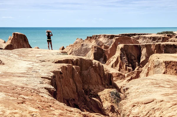 Ung kvinna på klipporna vid stranden — Stockfoto