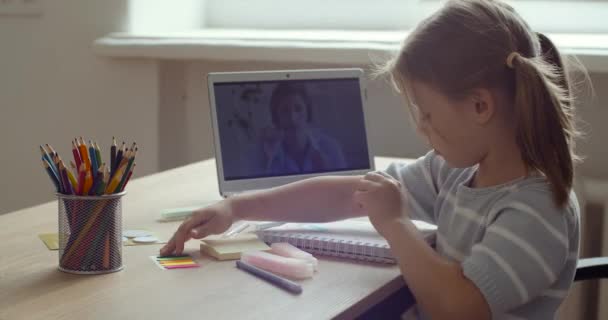 Side view tinédzser óvodás lány elfoglalt írásban vagy tanulási rajz által nézett laptop képernyőn során coronavirus magániskola. A gyerekek e-learning koncepciója, virtuális osztály a covid-19 idején — Stock videók