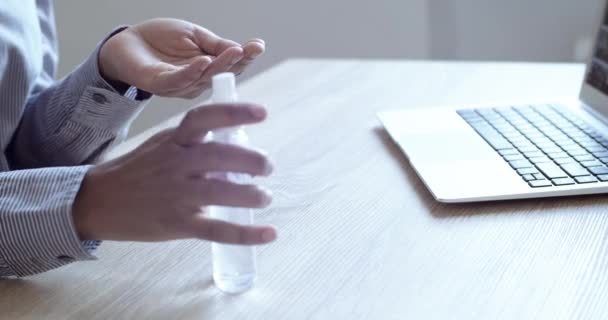 Close up mujer trata sus manos con gel de alcohol antiséptico y tipos en el teclado de la computadora. Trabajo remoto en casa. Las palmas de los brazos femeninos lavadas limpiadas con desinfectante de la bacteria de la infección del coronavirus — Vídeos de Stock