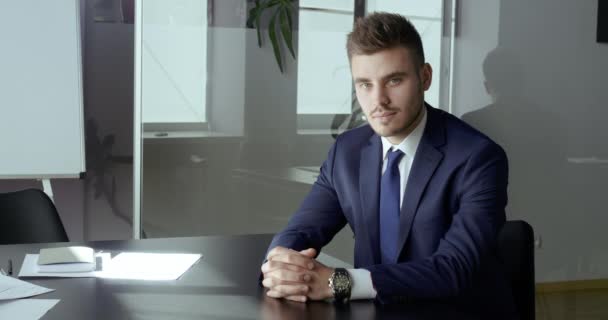 Zakelijk portret van ernstige jonge volwassen bebaarde man draagt blauwe pak zitten alleen geïsoleerd op kantoor tafel met gevouwen armen kijken oprecht en vol vertrouwen op camera, concept van succesvolle werkgever — Stockvideo