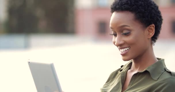 Ritratto di giovane donna freelance etnica sorridente in piedi all'aperto, che lavora da remoto, utilizza un dispositivo tablet per consultare i clienti via webcam, chatta con i colleghi online in rete — Video Stock