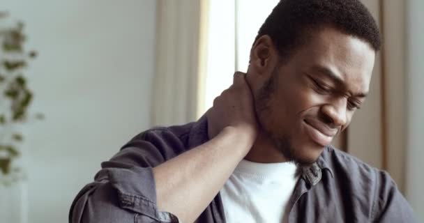 Retrato de jovem empresário afro-americano estudante freelancer sentado no escritório mesa em casa sentindo dor no pescoço cansado expressão tempo para descansar. misto raça cara sofrendo de dor no ombros — Vídeo de Stock