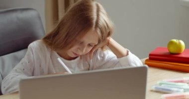 Uzaktan öğrenme, sarışın liseli kız bilgisayarla evden uzaktan eğitim alıyor ve deftere not alıyor. İnternet kursu izleyen genç kız öğrenci web kameralı öğretmenle konuşuyor.