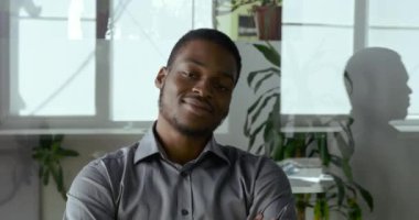 Kafadan çekilen portre kendinden emin genç Afrikalı Amerikalı iş adamı modern ofis odasında oturan başarılı yönetici kurucusu kollarını kavuşturup gülümseyerek poz veriyor.