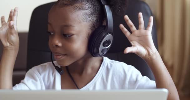 Retrato de niña afroamericana alumna de la escuela con auriculares que estudian en línea lejos de casa viendo lecciones de clase web o escuchando tutor por video llamada educación e-learning, aislamiento pandémico — Vídeo de stock