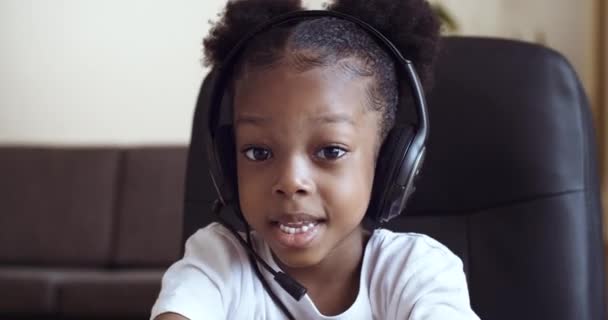 Web kamerasında, siyah tenli, kulaklık takan, sohbet eden, video kaseti çeken duygusal çocuk portresinin görüntüsü çocuk blogcusu, kameraya baş parmağını gösteriyor. — Stok video