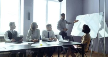 Erkek yönetici Afrikalı sunucu modern ofis yönetim kurulu toplantısında çok ırklı şirket çalışanları için konferans sunumu yapıyor. İş seminerinde hocalık eğitimi veren çok ırklı grup.