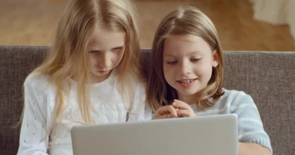 Lachende jonge twee kleine kinderen genieten van het gebruik van laptop samen kijken naar grappige cartoons video 's lachen spelen online surfen web op moderne computer apparaat ontspannen zitten op de bank thuis in de woonkamer — Stockvideo