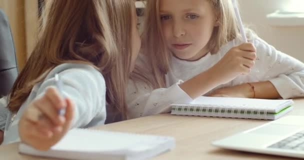 Dvě školačky přátelé sedí spolu u stolu psaní v notebooku dělat poznámky diskutovat cvičení mluví v lekci smích, malé holky dávat pět podporu navzájem, úspěch týmová práce koncepce — Stock video