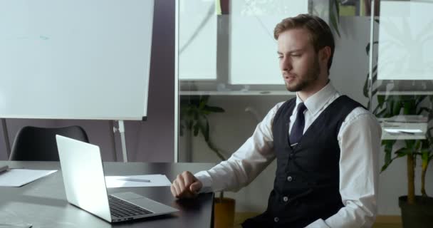 Serious young business man talking on video conference online in office. Handsome worker having video call on laptop computer indoor. Male professional advises clients vigorously during quarantine — Stock Video