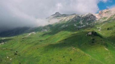Yükselen bulutların altındaki çarpıcı dağ manzarasının havadan görünüşü dağ yamacının yeşil vadisine gölge düşürüyor. Rusya 'nın Adygea Cumhuriyeti' ndeki Kafkaslar 'ın güzel doğası.