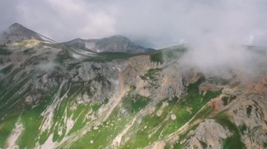 Bulutların hareket eden buharı altında çimlerle kaplı destansı bir sabah manzarası. Güzel Kafkas dağlarının havadan görünüşü. Turistler için harika bir yer. Seyahat ve yürüyüş konsepti