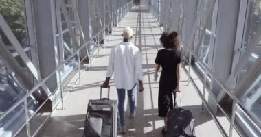 Arkadan bir çift genç Afro-Amerikalı erkek arkadaş koca ve eş havaalanı terminalinde bavullarını birlikte taşıyarak gezmeye gidiyorlar.