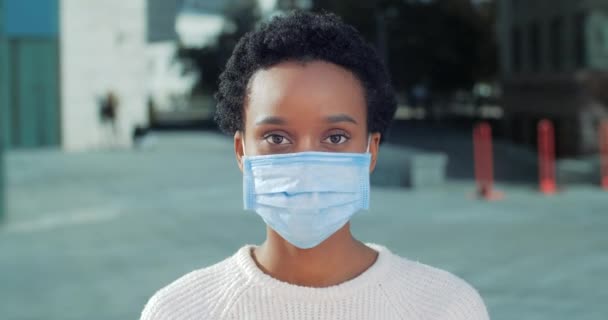 Retrato de afro-americano doente infeccioso paciente feminino em máscara protetora médica fica sozinho olha para câmera cruza braços na frente de seus shows proibição sinal de parada coloca restrições — Vídeo de Stock