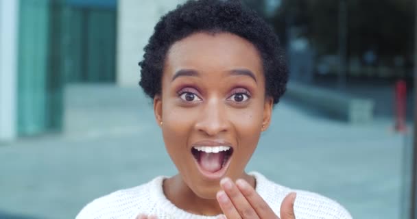 Primer plano de la cara femenina conmocionó las emociones Chica afroamericana con el maquillaje ideal y los ojos de par en par en sorpresa, sonriendo con dentadura cubriendo su boca con la mano bien cuidada. Mujer aprende buenas noticias feliz dice wow — Vídeo de stock