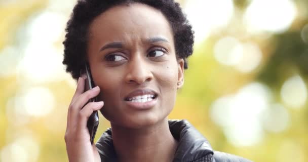 Close-up portret Afryki amerykanka dziewczyna bizneswoman student stojący na zewnątrz sam mówi przez telefon używa smartfona do komunikacji czuje szok niespodzianka rozwiązuje problemy biznesowe zdalnie — Wideo stockowe