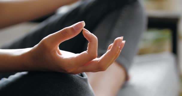 Mulher vestindo roupas de jeans casuais sentado no sofá no quarto em posição de lótus com pernas cruzadas, fazendo ioga em casa, praticando asanas, ganhando energia, relaxante, conceito de harmonia zen concentrado, close-up — Vídeo de Stock