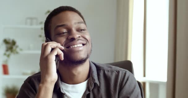 Portrait of happy smile afo american guy business freelance student sitting at home office using smartphone device to communicate on mobile phone answers remotely consulses to client — Stok Video