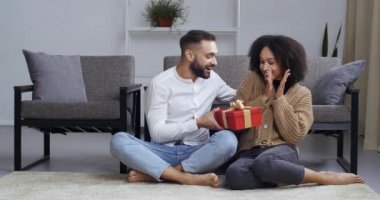 Çok ırklı yeni evli çiftler yeni yıl sevgililer gününü kutlamak için evde oturuyorlar. Afro-Amerikalı kız, Kafkasyalı kocadan yıldönümü hediyesi olarak karton kutu alıyor.