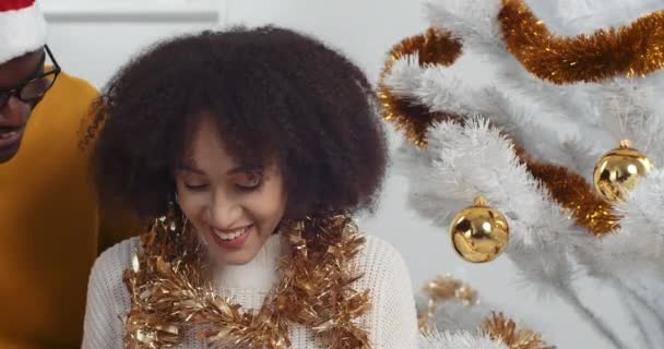 Close up Afro amerykańska para zakochanych zebranych w domu w pobliżu urządzone migoczące choinki, kochający czarny mąż sprawia niespodziankę dla ukochanej kręcone żona dając pudełko prezentów gratuluje Nowy Rok wakacje — Wideo stockowe