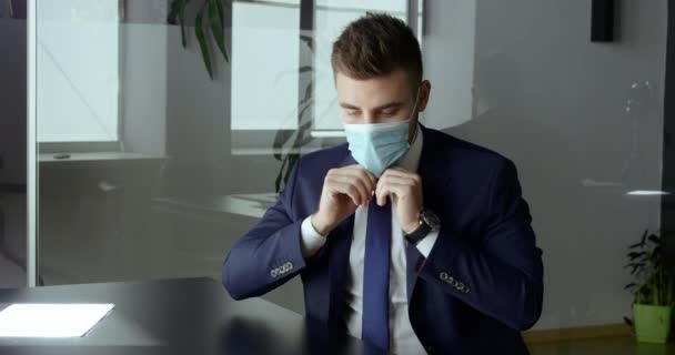 Kaukasische knappe zakenman zet medisch masker op zijn gezicht beschermt tegen infectie respiratoire virus covid tijdens epidemie pandemie, nieuwe sociale regels norm, bedrijf tijdens quarantaine close-up — Stockvideo