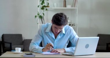 Eksantrik aktif genç yazar masa başında çalışıyor, kalemle yazı yazıyor, fikirler üretiyor, şiirler yazıyor, hatalar yapıyor, belgeleri parçalıyor, kağıt parçaları atıyor, beyin fırtınası konsepti yaratıyor.