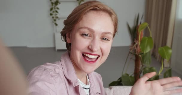 Retrato feliz bastante caucásico mujer adolescente chica sonriendo la cara saludando de la mano hablando con la webcam hacer videollamada en casa hablando de chat por videollamada virtual zoom aplicación de reunión en línea. Cerrar vista de cámara web — Vídeos de Stock