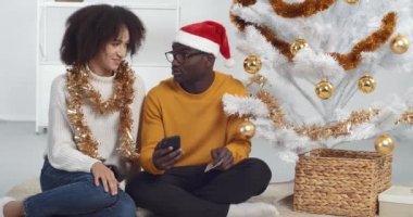 Afro-Amerikalı aile çifti akıllı telefon ve kredi kartıyla online alışveriş yapıyor, internetten yeni yıl hediyeleri alıyor, Noel arifesi indirimi, güvenli ödeme, e-ticaret ve e-alışveriş kavramı