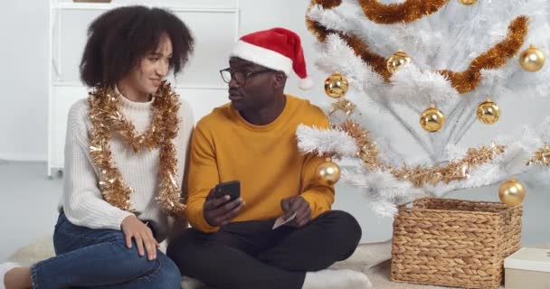 Famiglia afro-americana coppia uomo e donna fanno acquisto online utilizzando smartphone e carta di credito, acquistare regali di Capodanno su internet, Vigilia di Natale vendita, pagamento sicuro, e-commerce e e-shopping concetto — Video Stock