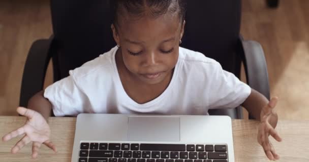 Pandangan atas anak sekolah afro american duduk di laptop merasa stres karena kegagalan. Anak bingung menebarkan tangannya ke samping dalam frustrasi mengetik pada papan ketik melakukan pekerjaan rumah yang sulit — Stok Video