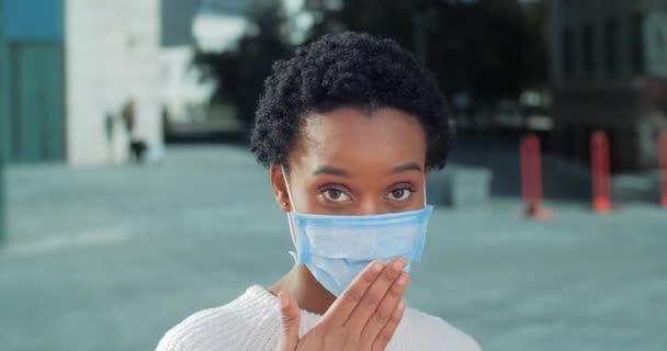 Coquette flicka afrikansk amerikansk svart kvinna patient står isolerad utomhus bär skyddande medicinsk mask känns chock förvåning glädje täcker munnen med händerna vågor på sig själv tittar på kameran — Stockvideo