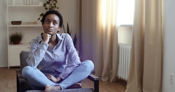 Tired afro american girl black woman feeling stress sorrow sadness suffering from headache sitting on chair in living room holding head from noise of naughty child girl daughter demanding attention — Stock Video