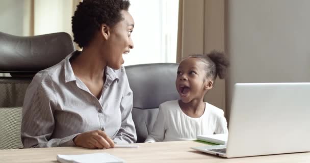 Afro-amerikan kadın öğretmen anne kız kardeş tatlı kıza ev ödevi ile yardım ediyor. Coronavirus sırasında kendi kendine ders veriyor. Virüs salgını sırasında internet bilgisayarı kullanarak uzaktan öğreniyor. — Stok video