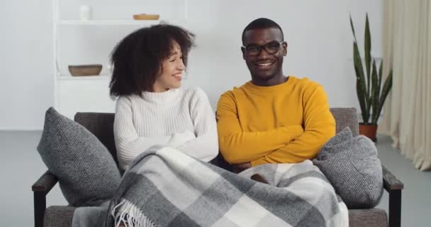 Souriant heureux jeunes mariés amis frère et soeur petit ami et petite amie assis ensemble sous la couverture sur le canapé à la maison riant bruyamment sincèrement souriant regarder la télévision vidéos drôles sur Internet — Video