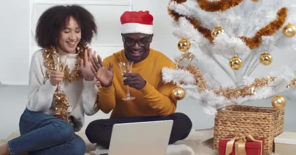 Pria Afrika dan wanita kulit hitam merayakan tahun baru bersama-sama selama virus pandemi isolasi dari jarak jauh mengucapkan selamat kepada keluarga melalui video chat menggunakan laptop melambaikan tangan halo minum sampanye — Stok Video