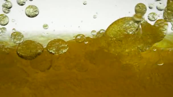 L'olio di girasole giallo è mescolato con acqua, non si dissolve. Le lampadine a bolle d'aria galleggiano nei liquidi creando fantasie, texture e sfondi. Colpo al rallentatore del liquido dell'olio da versare. Vitamina E sana — Video Stock