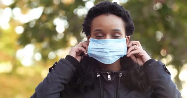 Menina de raça mista meninas americanas africanas mulher doente infeccioso senhora vestindo máscara cirúrgica médica protegendo sua saúde de coronavírus doença respiratória durante pandemia olhando para a câmera — Vídeo de Stock