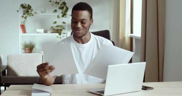 Retrato afro-americano mestizo hombre de negocios leyendo documentos informe papel proyecto información carta banco financiación aviso regocija siente felicidad celebrando triunfo sentado en fuente de portátil — Vídeos de Stock