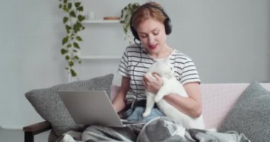 Dost canlısı, beyaz, güler yüzlü, sosyal bir kız. Kulaklık takan, mikrofon takan, elinde beyaz kedi tutan genç bir kadın. Sevdiği tüylü hayvanı internetteki görüntülü sohbet konferansında konuşuyor.