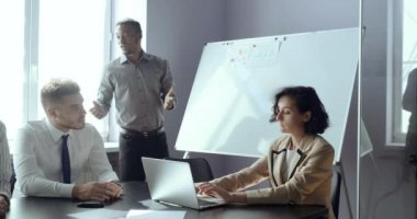 Ofis görüşmelerinde karatahtaya oturan Afrikalı erkek öğretmen, iş kadınlarına dizüstü bilgisayar ve Kafkas erkek projeleri hakkında fikir beyan ederek konferanslar veriyor.