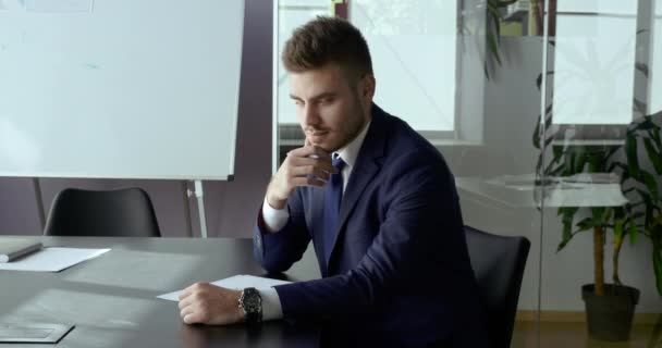 Πορτρέτο του στοχαστικού αφεντικού των επιχειρήσεων κάθεται στο τραπέζι στο γραφείο στη σύγχρονη εταιρεία διαβάζει το συμβόλαιο έγγραφο γυρίζει αρσενικό κεφάλι κοιτάζει κάμερα δείχνει σημάδι εντάξει υποστήριξη σύμβολο της επιτυχίας καλές ειδήσεις — Αρχείο Βίντεο