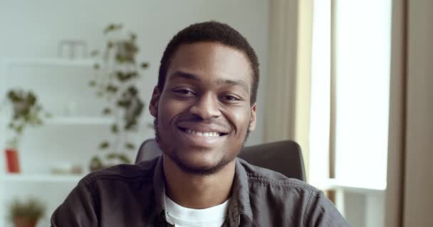 Close-up cropped shot of male face with black skin ethnic man afro american guy businessman looking straight into camera smiling sincerely friendly with toothy white teeth, mixed race person portrait — Stok video