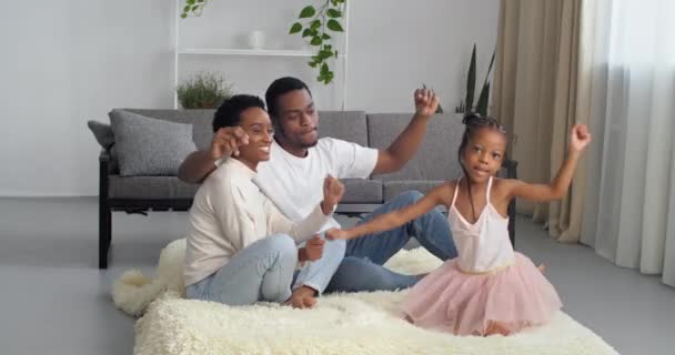 Happy people friendly aimant afro famille américaine femme noire maman et ethnique jeune père couple famille avec petite fille mignonne drôle enfant fille danse à la maison assis sur le sol du salon en s'amusant — Video