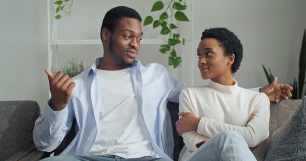 Portret dwojga ludzi afro amerykański facet i czarny dziewczyna etniczne millennial dziewczyna siedzi razem na kanapie w domu rozmowy dialog przekazując informacje dzielone żona słuchając jej mąż uśmiechnięty — Wideo stockowe